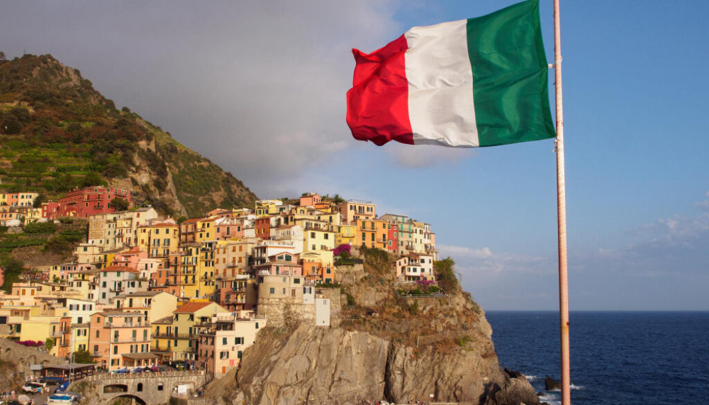Italian Flag on mountain by sea against sky